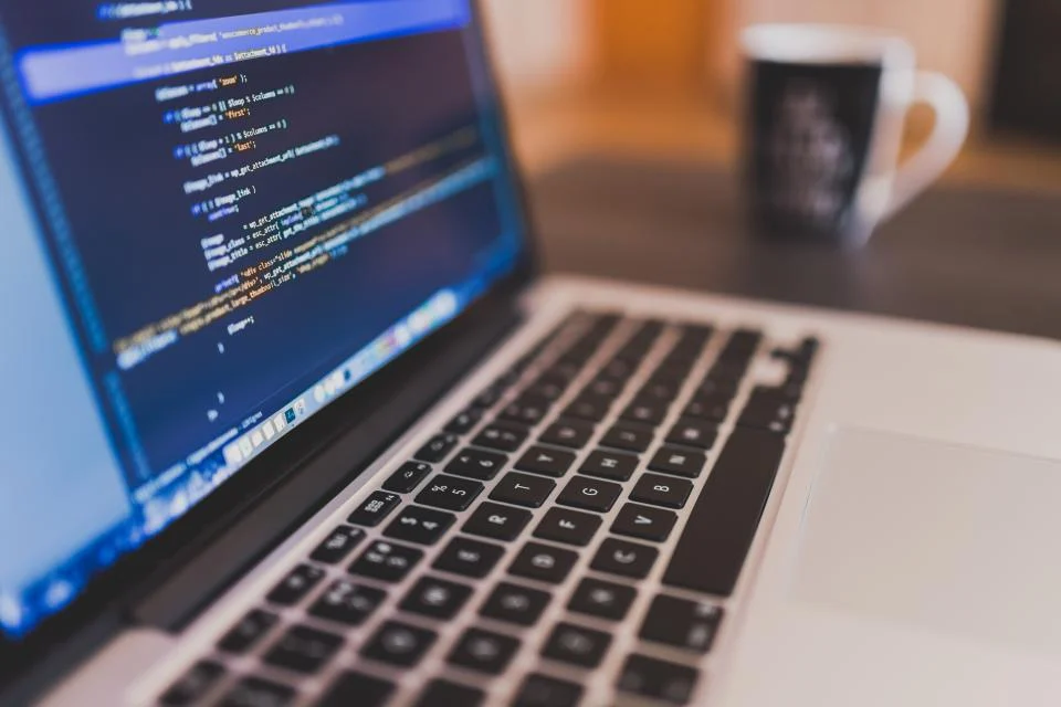 Website development: code editor open on a laptop next to a cup of coffee